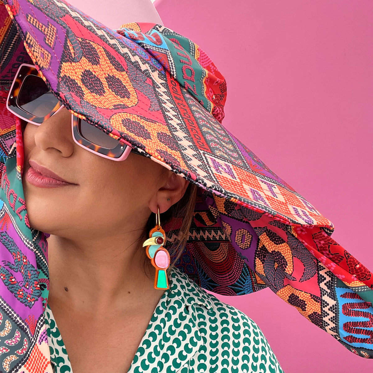 Woman wearing a colorful patterned visor against a pink background